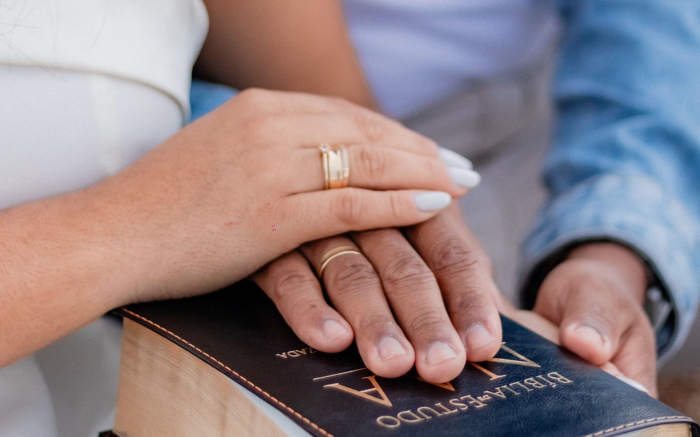 A couple placing their hands together on a Bible