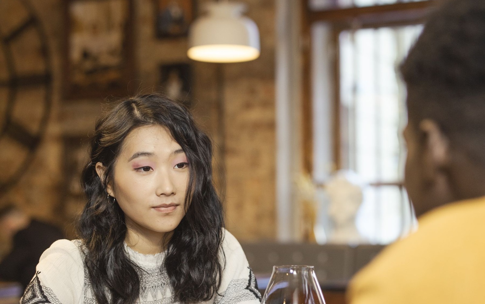 An Asian woman listening to her date during a restaurant conversation