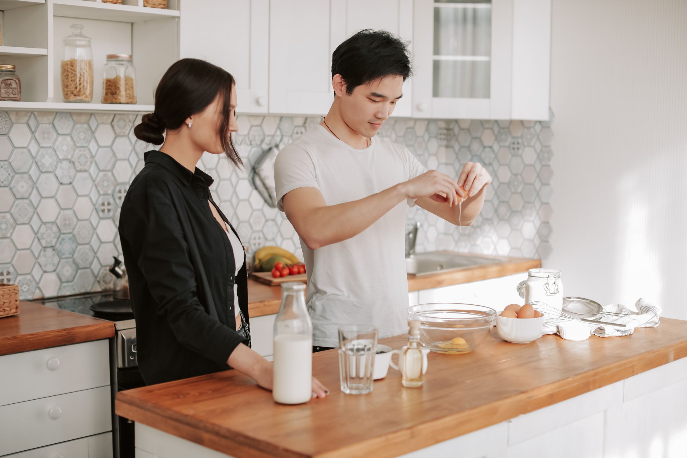 An Asian man and Caucasian woman cooking together at home